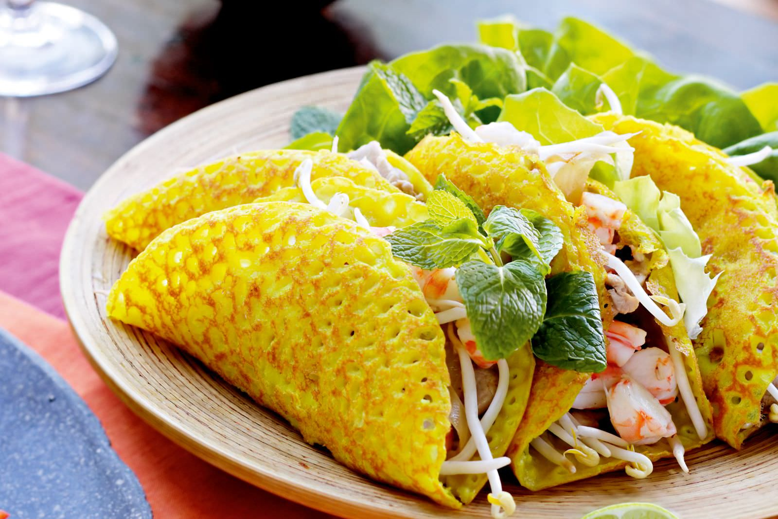 A close-up of crispy yellow Banh Xeo, a popular street food on "hanoi day tours".