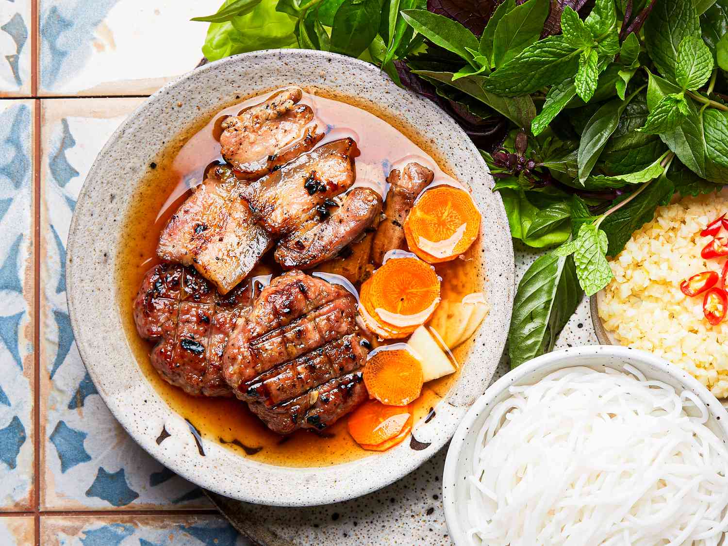 A close-up of a bowl of Bun Cha with grilled pork patties and sliced carrots in a savory broth, a classic meal on "hanoi day tours"