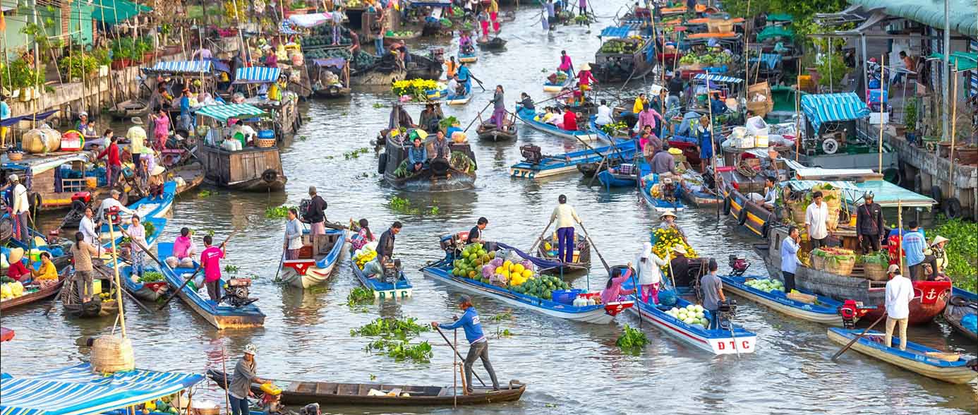 Vietnam & Cambodia Family Holidays: Vibrant floating market on the Mekong River, showing many boats selling fresh produce, a popular family activity.