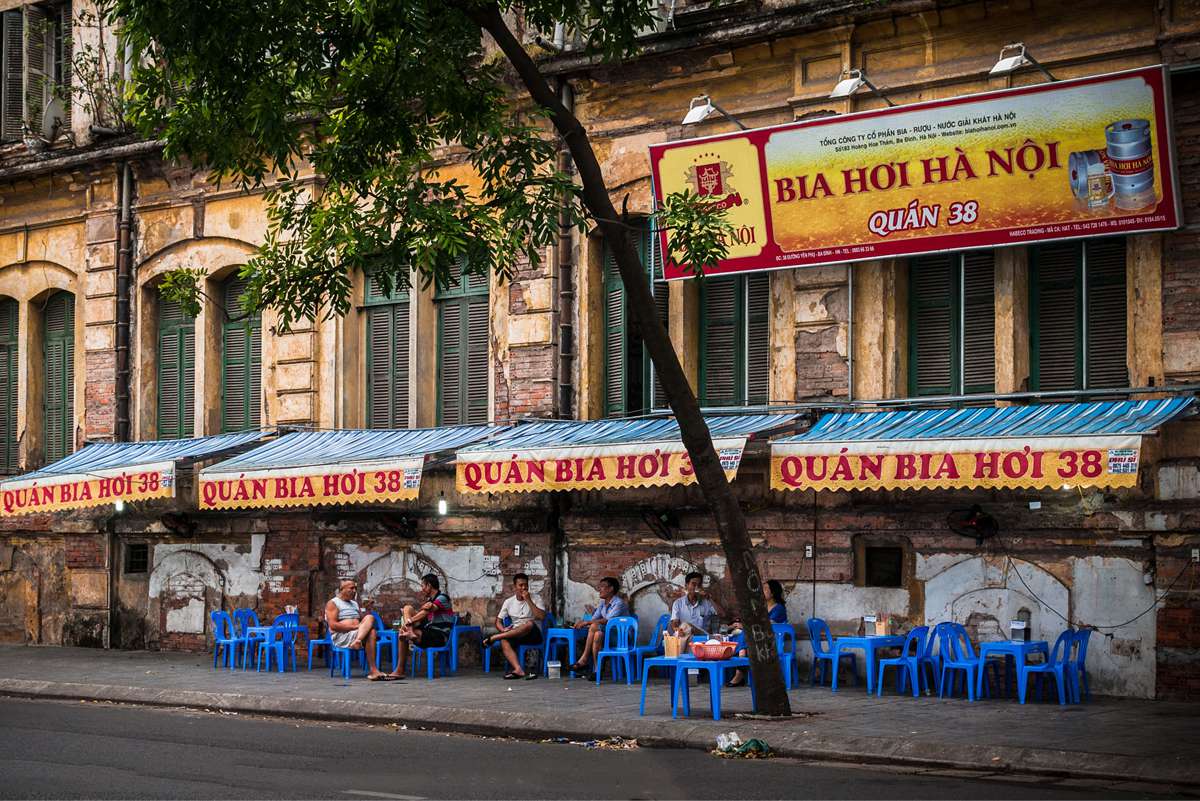 Old Town Beer: Local 'Bia Hơi Hà Nội' establishment on the street sidewalk with people sitting on blue chairs, showcasing the casual Old Quarter drinking culture