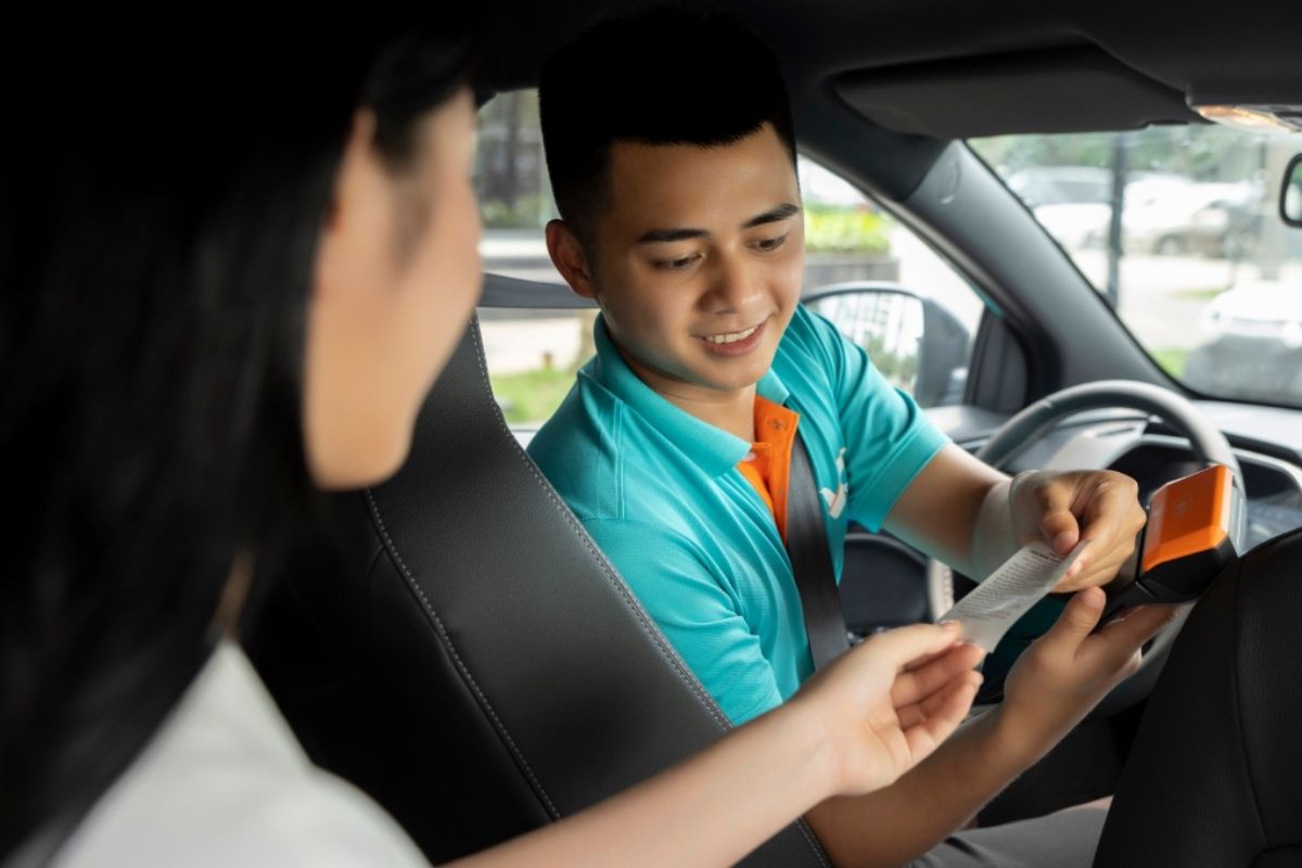 Taxi and Ride-Hailing Drivers: Driver in a service uniform handing a receipt or device to a passenger in the car, illustrating modern travel services.