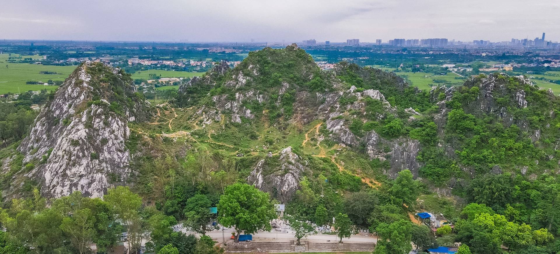 An aerial view of the rugged, karst peaks of Tram Mountain near Hanoi, a scenic hiking option for hanoi day tours
