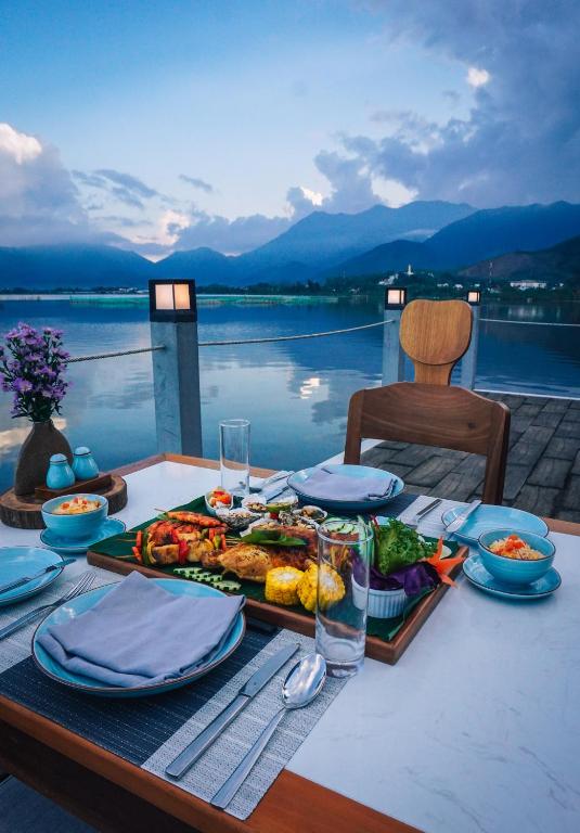 Outdoor lagoon-side dining setup at Vedana Lagoon Resort Vietnam with traditional Vietnamese dishes and breathtaking mountain views.
