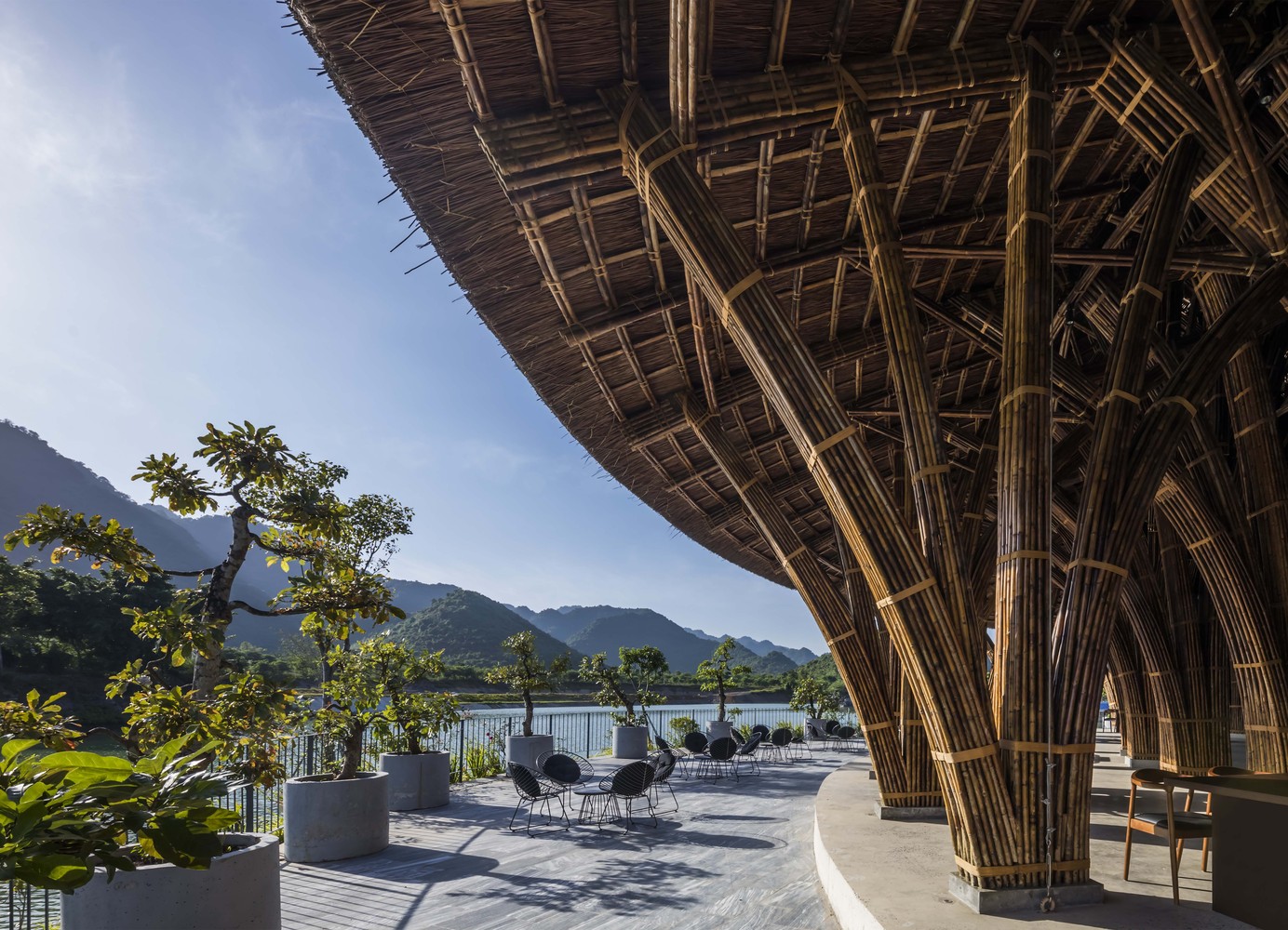 Open-air bamboo architecture at Vedana Lagoon Resort Vietnam with outdoor seating and scenic mountain-lagoon backdrop.