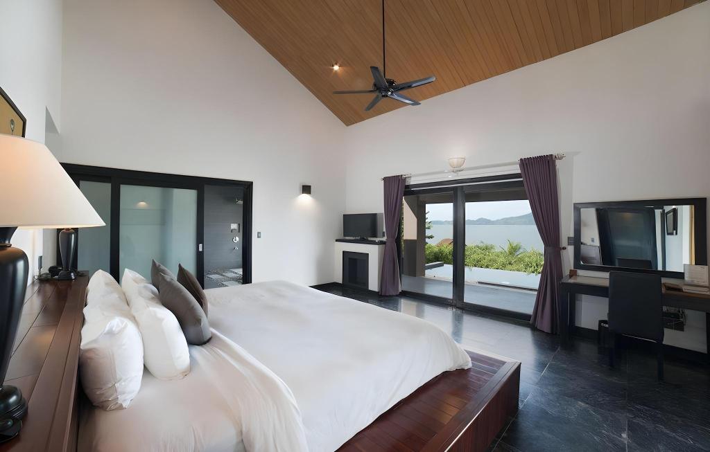 Spacious lagoon-view bedroom at Vedana Lagoon Resort Vietnam featuring modern décor, large windows, and serene mountain scenery.