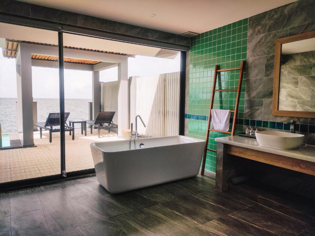 Luxury bathroom with freestanding tub and private terrace overlooking the water at Vedana Lagoon Resort Vietnam over-water villa.