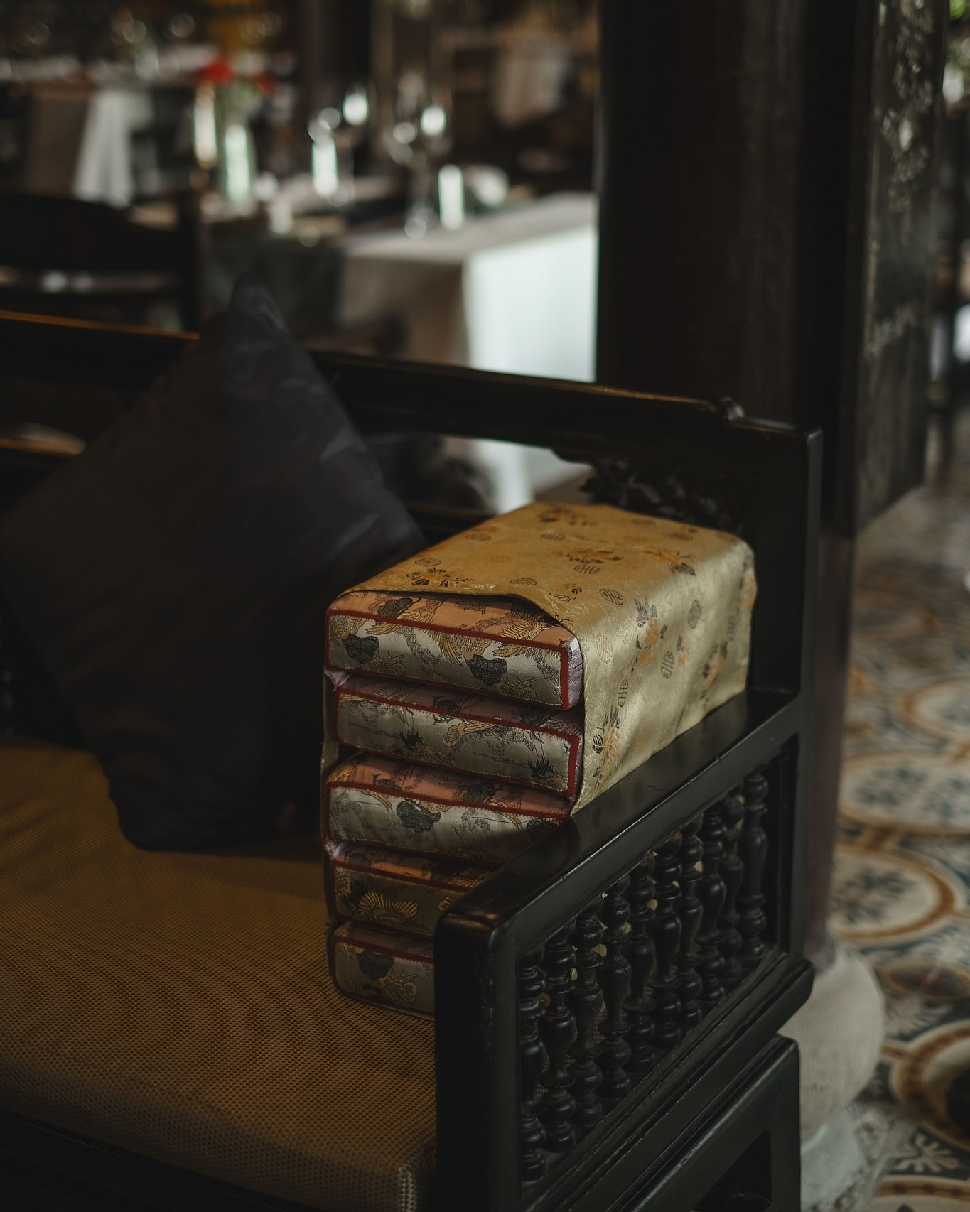 Elegant silk cushion on carved wooden chair at Ancient Hue Garden Houses, showcasing traditional Vietnamese craftsmanship and refined interior design.