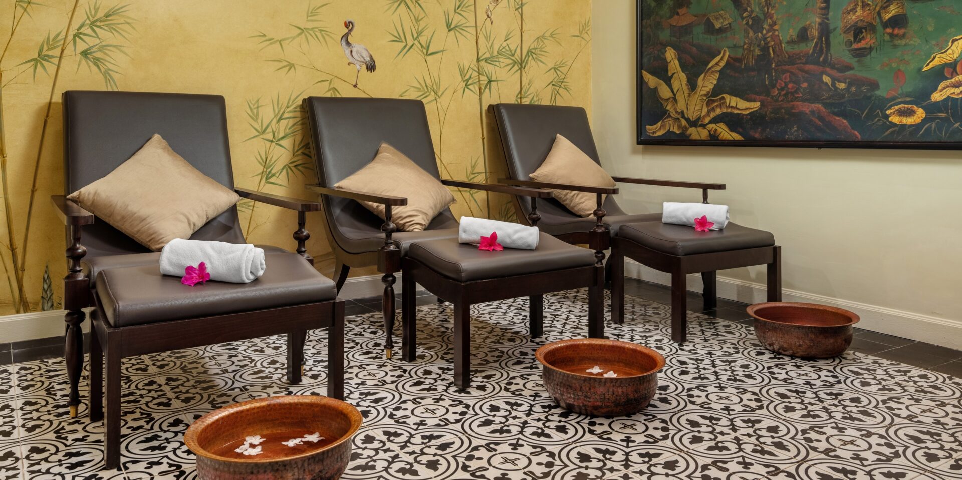 Tranquil spa corner at Ancient Hue Garden Houses featuring wooden chairs, floral decor, patterned tiles, and warm traditional Vietnamese ambiance.