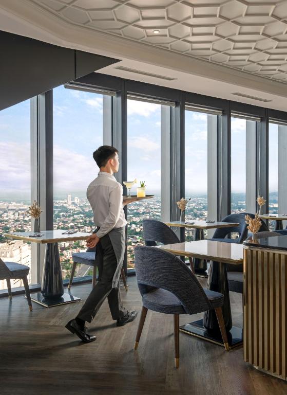 Professional waiter serving guests at Melia Vinpearl Hue sky lounge, offering panoramic city views and five-star dining experience.