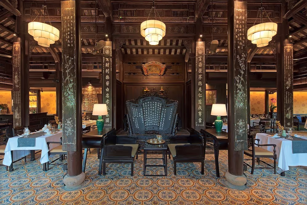 Luxurious dining hall at Ancient Hue Garden Houses with royal décor, carved wooden columns, vintage furniture, and authentic imperial ambiance.
