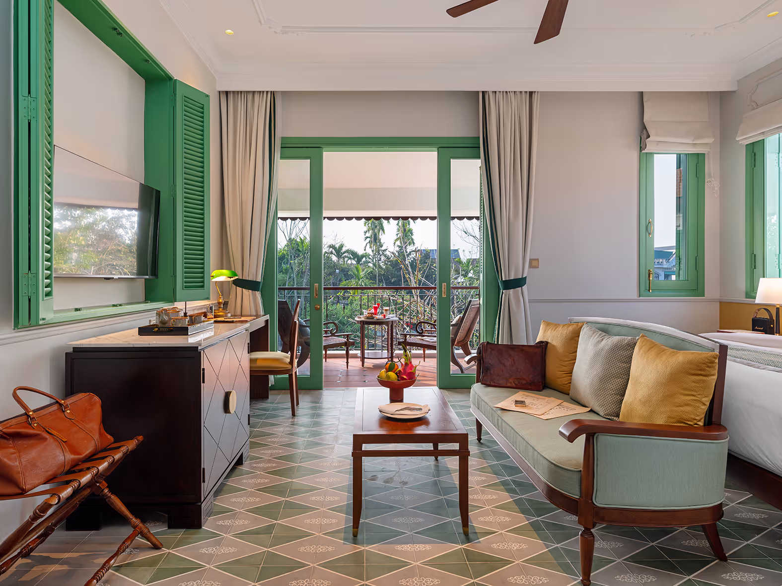 Bright and elegant French villa room at Ancient Hue Garden Houses featuring green shutters, vintage furniture, and a balcony garden view