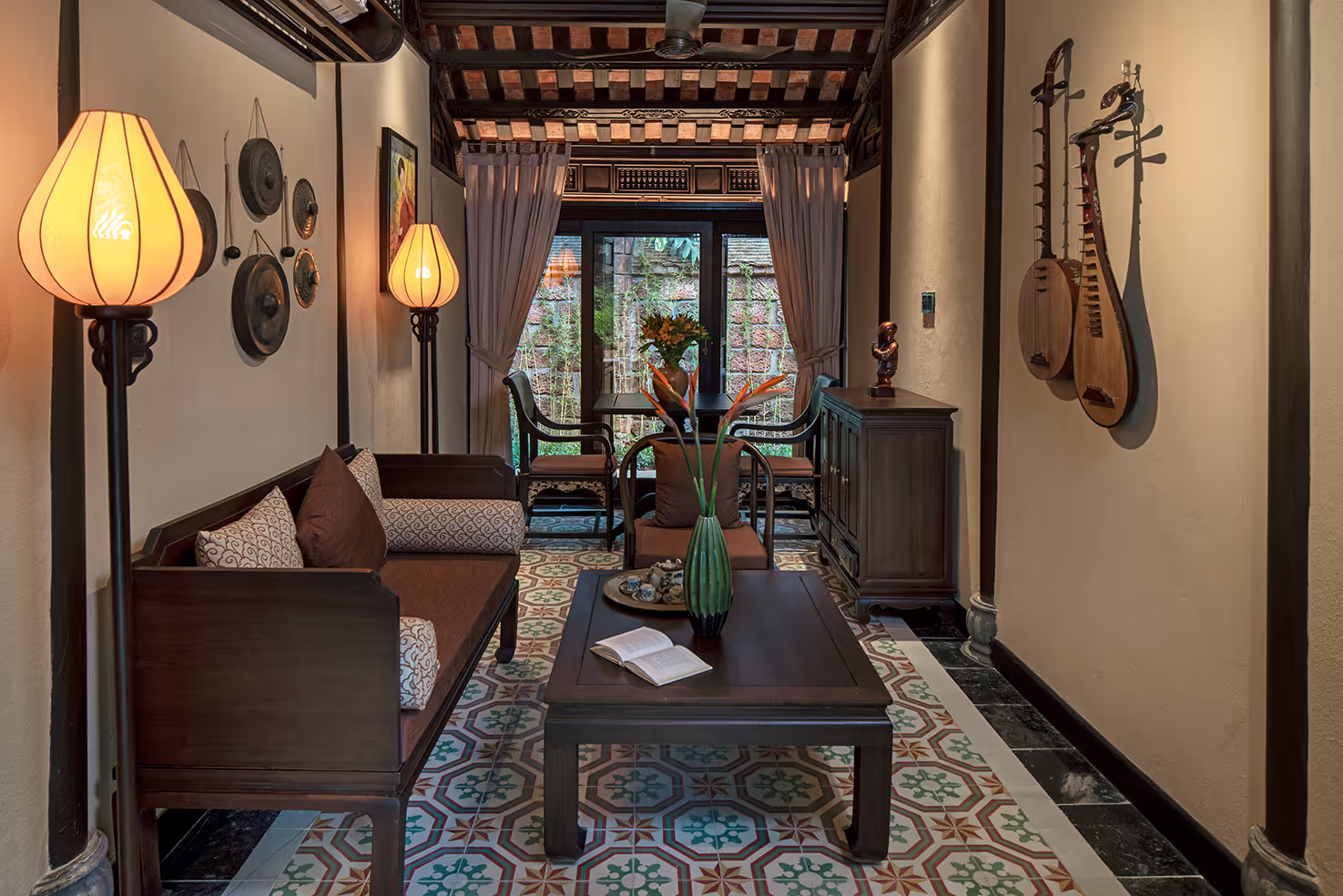 Cozy living area at Ancient Hue Garden Houses with warm lanterns, traditional décor, and elegant Vietnamese musical instruments on display.