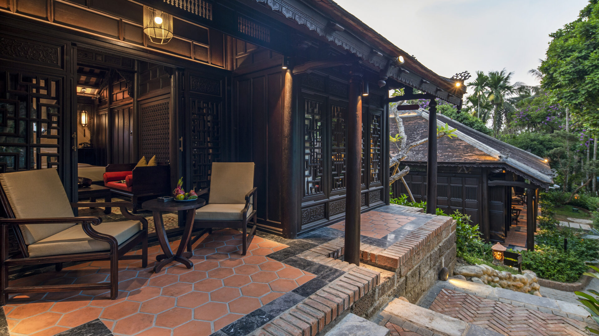 Elegant wooden terrace and traditional architecture at Ancient Hue Garden Houses, featuring handcrafted lattice doors, lanterns, and serene garden views.