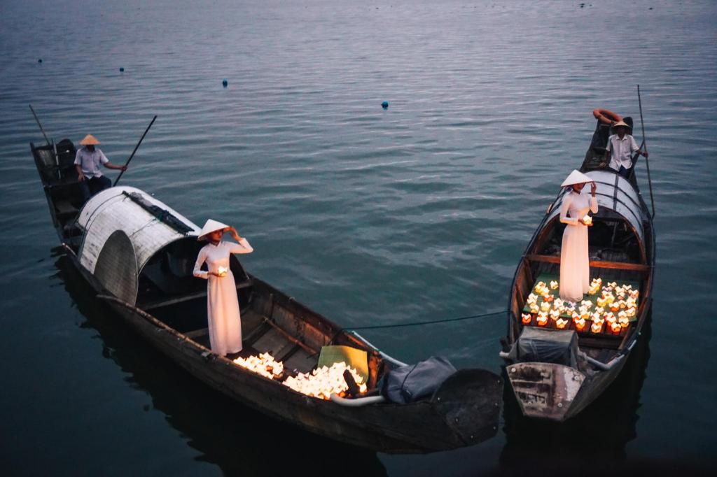 Traditional boat lantern ceremony near Vedana Lagoon Resort Vietnam, featuring women in áo dài releasing candles on the Perfume River.