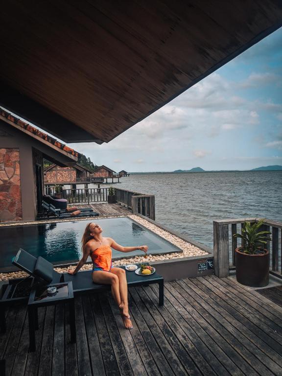 Guest relaxing by private infinity pool at Vedana Lagoon Resort Vietnam over-water villa with panoramic lagoon views.