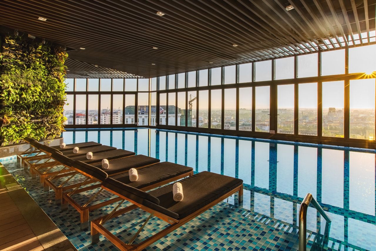 Indoor swimming pool at Melia Vinpearl Hue with floor-to-ceiling glass and cityscape views, perfect for relaxation and rejuvenation.