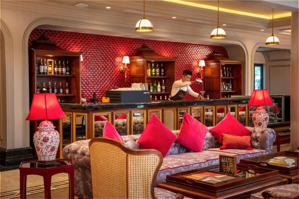 Stylish bar at silk path grand hue hotel with red accents, vintage furniture, and skilled bartender.