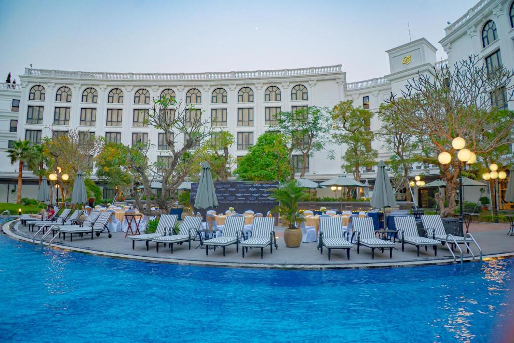 Outdoor pool area at silk path grand hue hotel surrounded by sun loungers and lush greenery. 