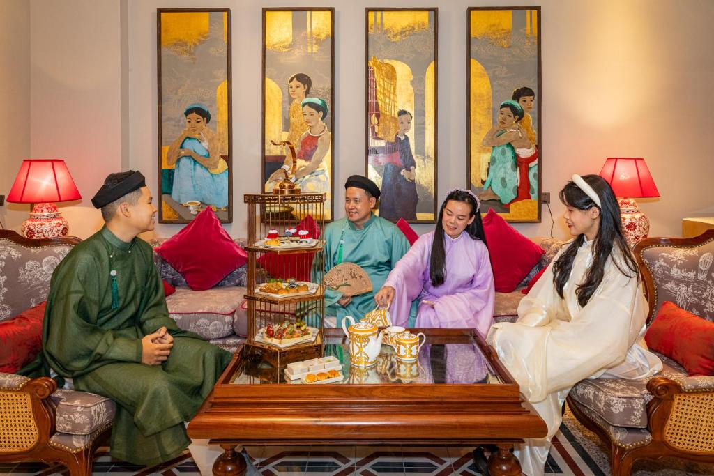 Guests in traditional Vietnamese attire enjoying afternoon tea at silk path grand hue hotel in Hue.