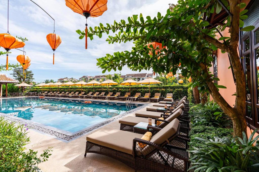 Allegro Hoi An swimming pool surrounded by greenery and sun loungers