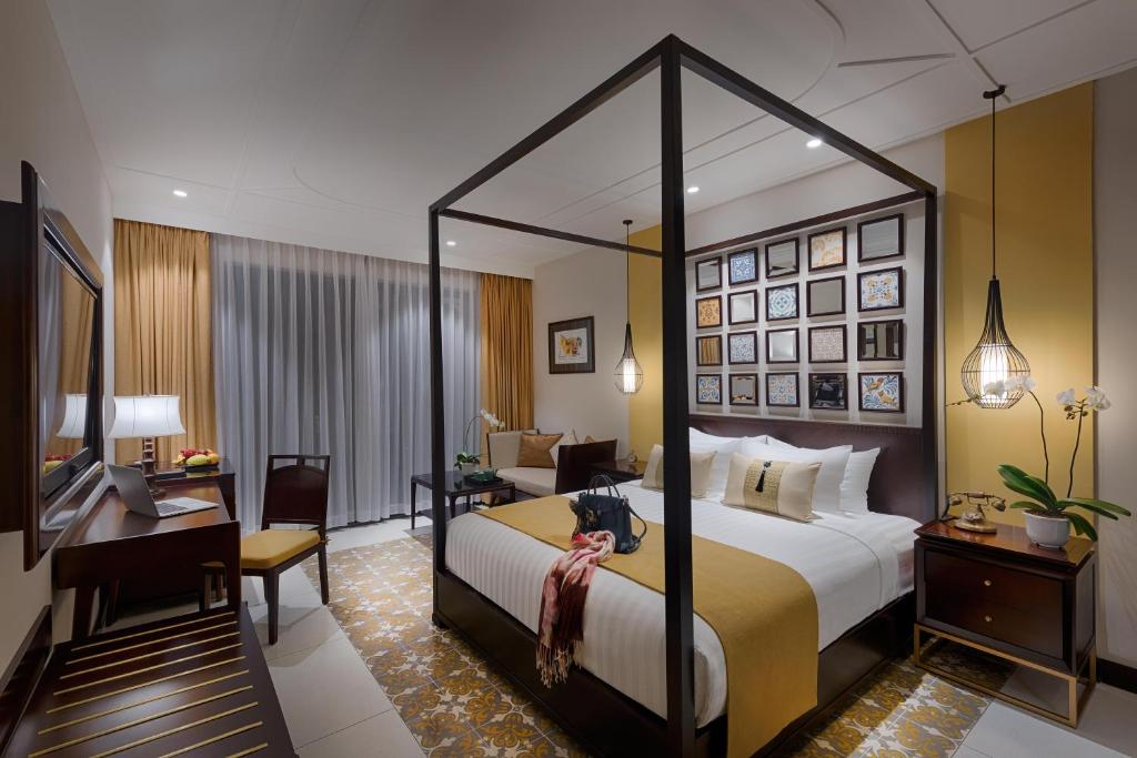 Allegro Hoi An bedroom featuring canopy bed and warm tones