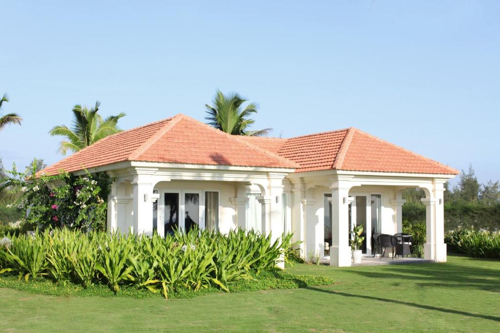 Cozy beachfront villa with red-tiled roof and tropical greenery at Boutique Hoi An Resort.