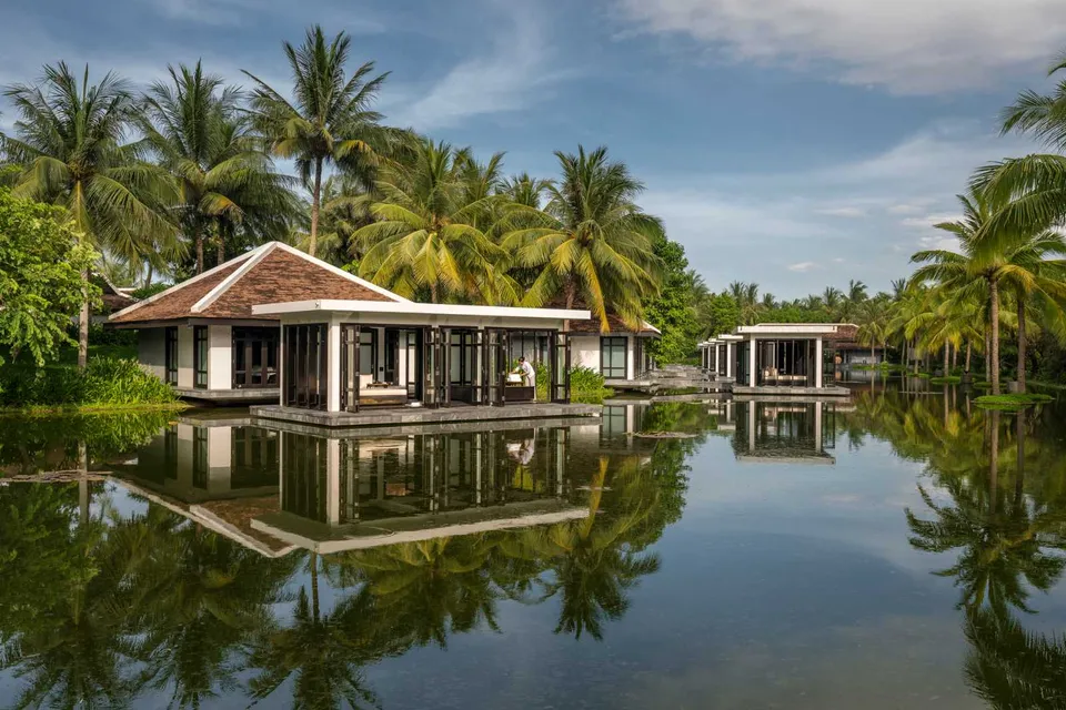 Overwater villas surrounded by palm trees and lagoon at Four Seasons Resort The Nam Hai, Hoi An.