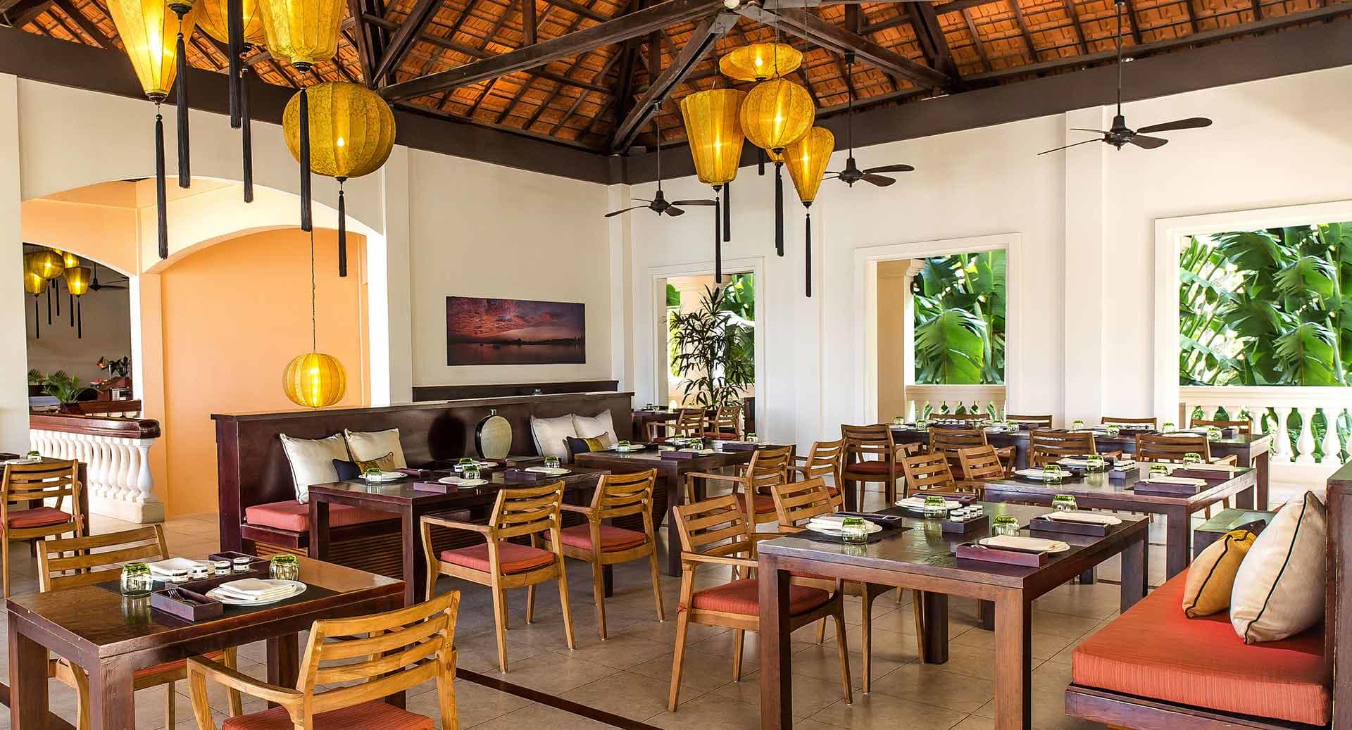 Lantern-lit dining room with tropical charm and wooden interiors at Hoi An Riverside Restaurant, Anantara Hoi An Resort.