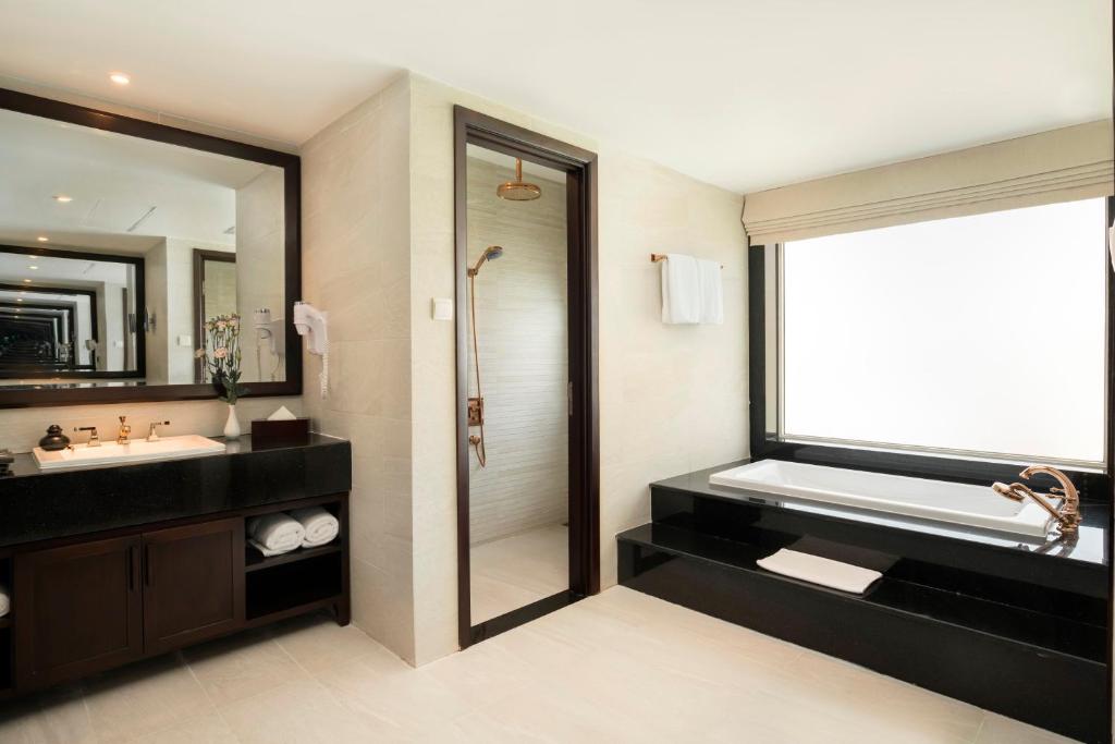 Modern bathroom with bathtub, rain shower, and marble counter inside Boutique Hoi An Resort.