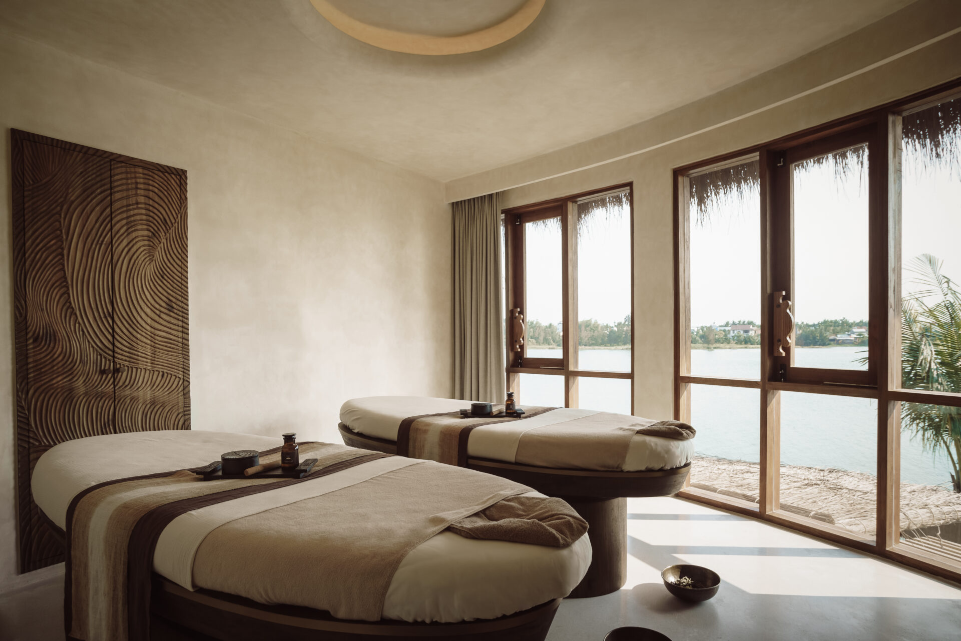 Lumina Spa treatment room at Namia River Retreat offering twin massage beds, river views, and calming natural light.