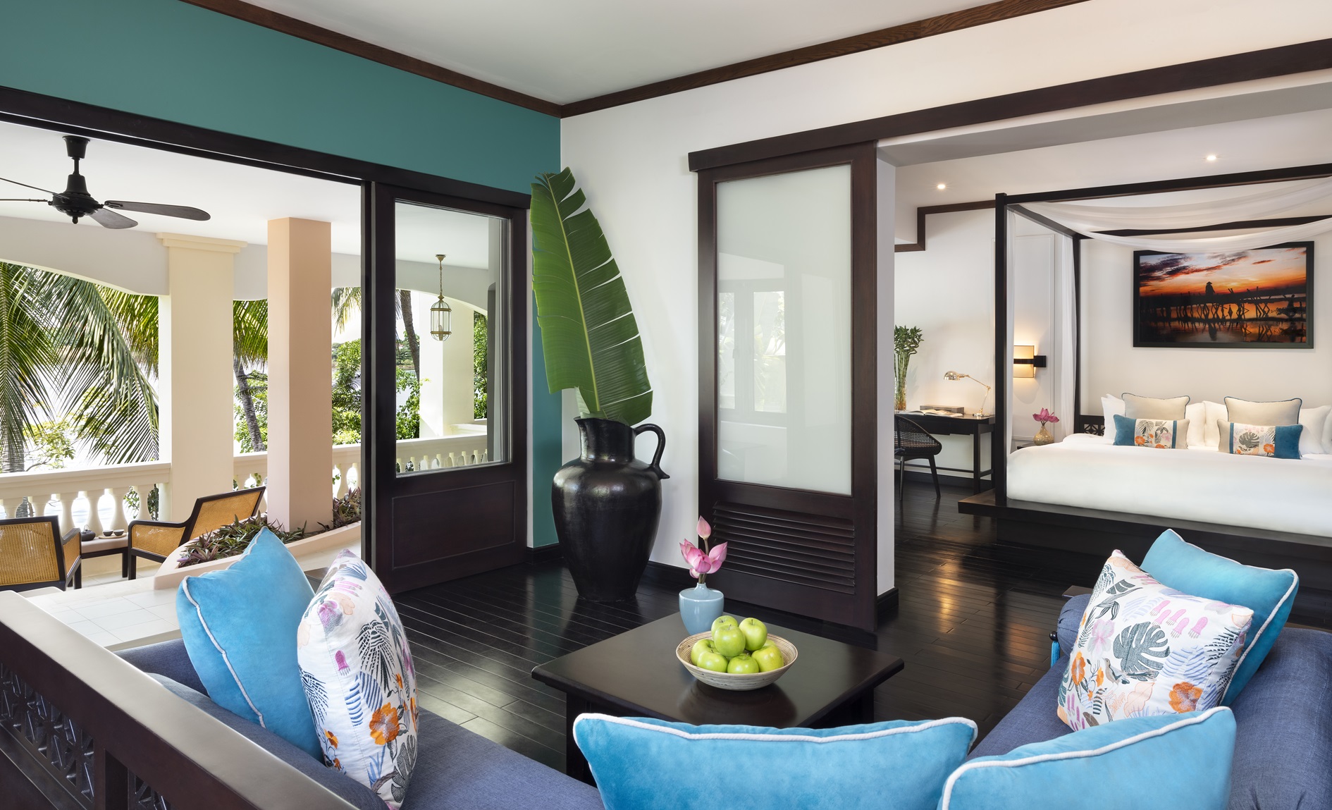Spacious riverside suite with blue accents, open balcony, and garden views at Anantara Hoi An Resort.
