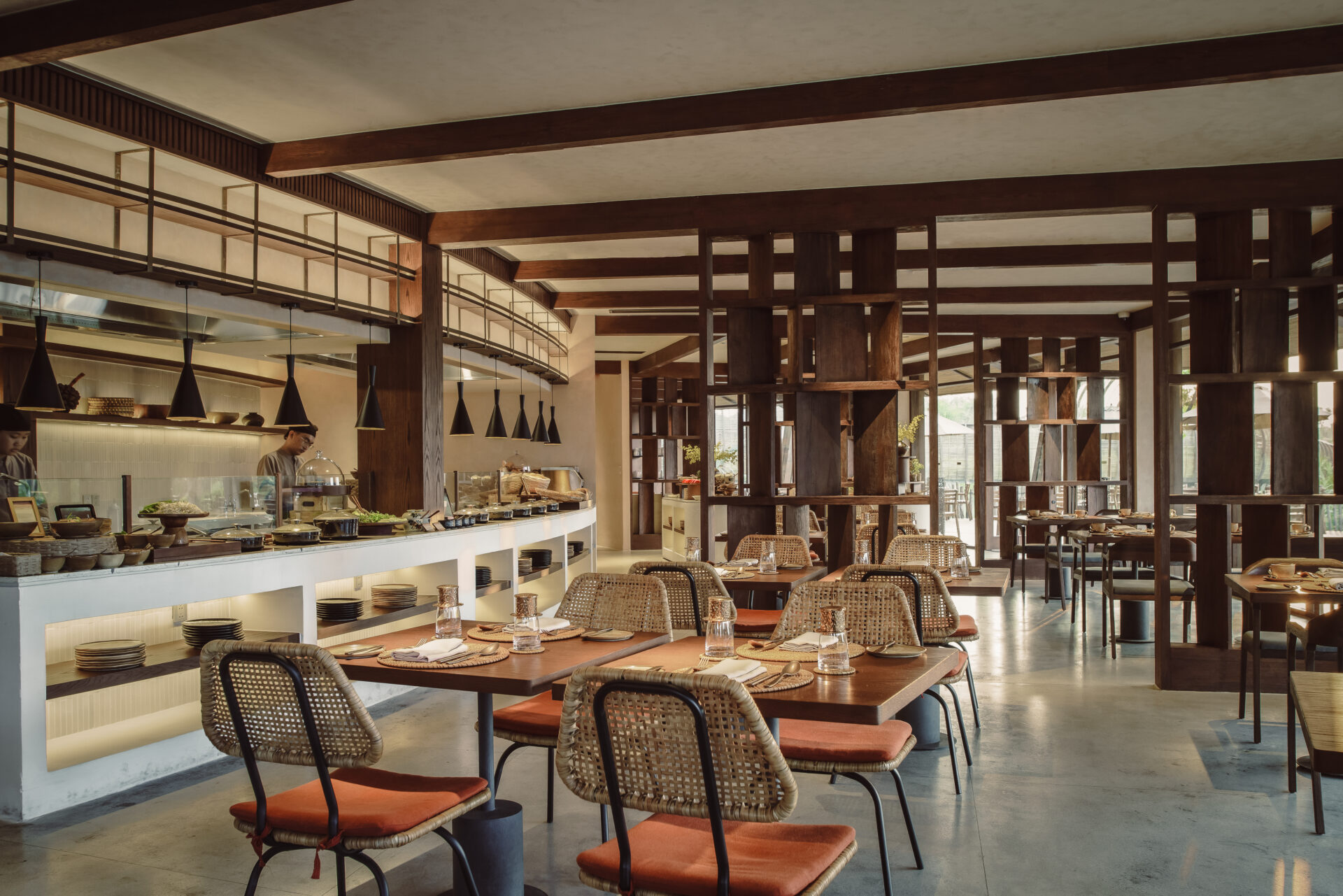 Elegant dining area at Namia River Retreat featuring open kitchen, wooden interiors, warm lighting, and contemporary Vietnamese restaurant design.