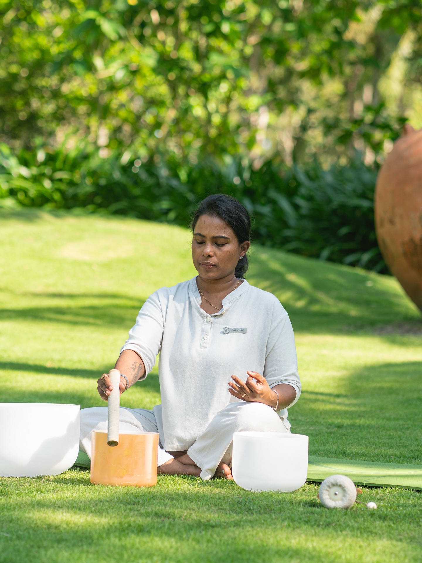 Wellness expert performing sound bowl therapy outdoors at Four Seasons Resort The Nam Hai, Vietnam.