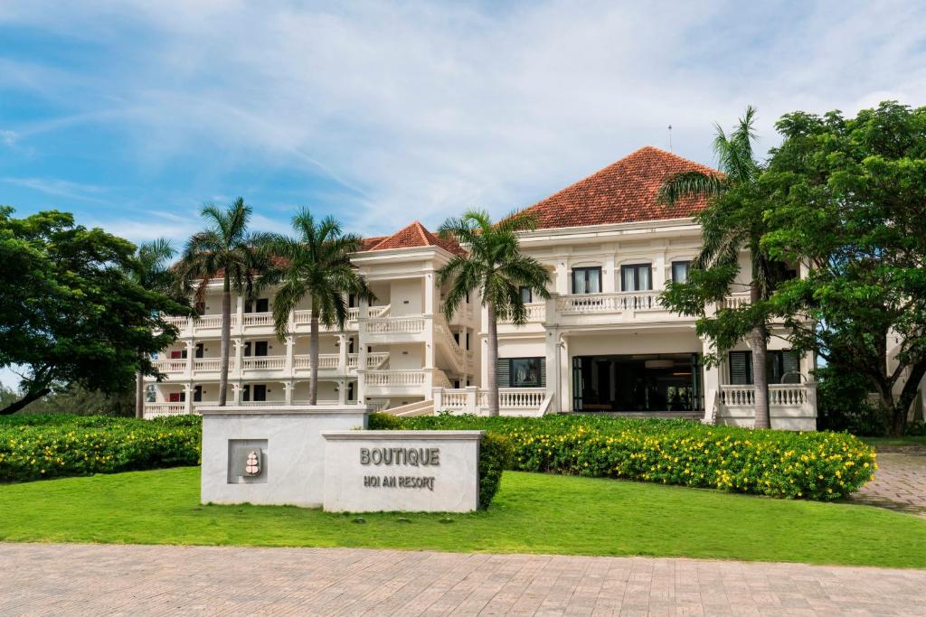 Elegant French colonial architecture surrounded by palm trees and gardens at Boutique Hoi An Resort in Central Vietnam.