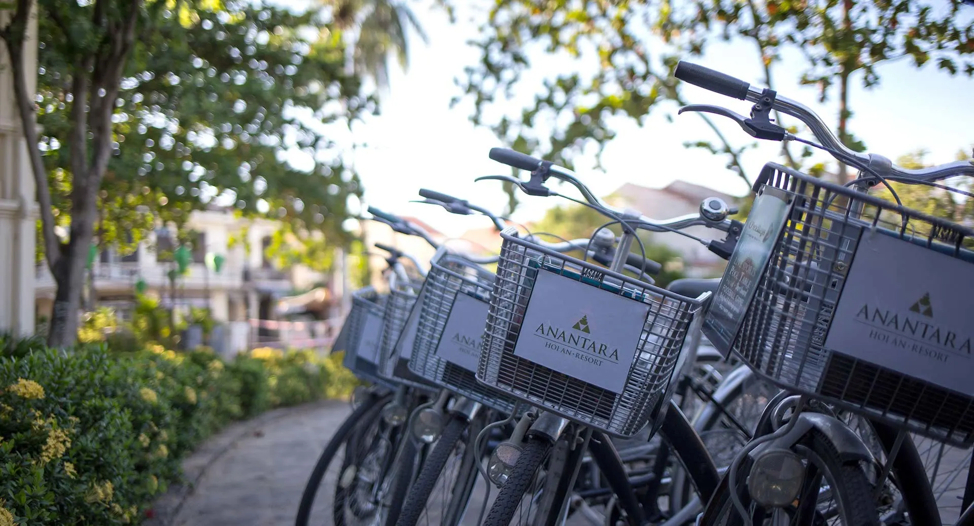 Complimentary bicycles lined up under tropical sunlight for guests to explore Hoi An from Anantara Hoi An Resort.