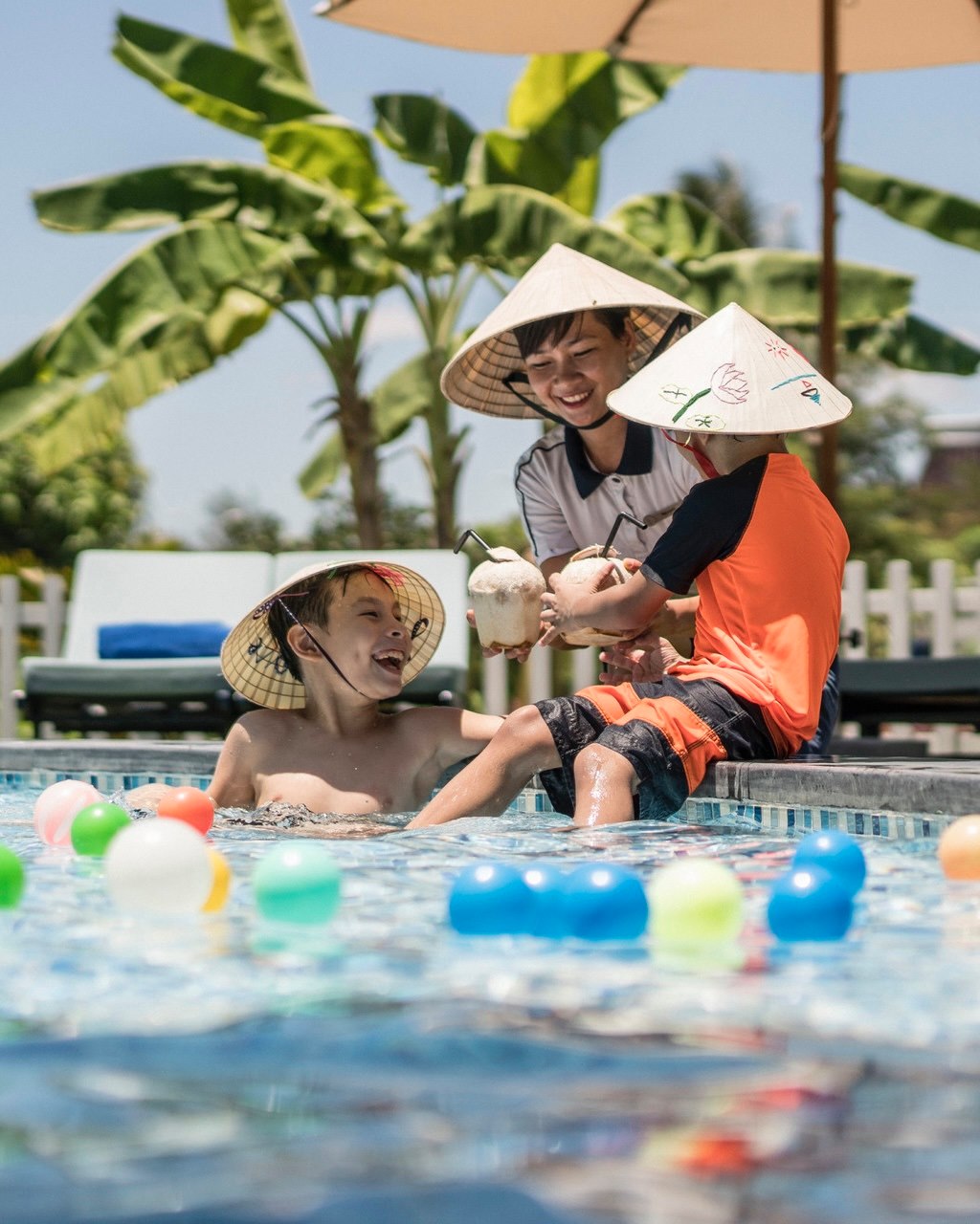Children enjoying poolside coconut drinks during family activities at Four Seasons Resort The Nam Hai.