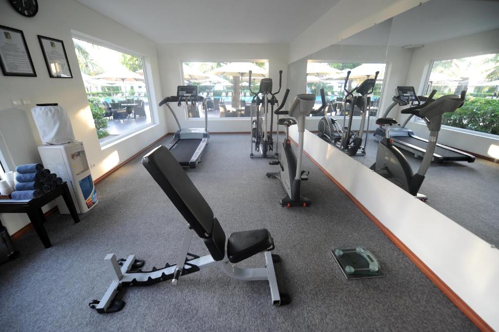 Modern fitness center with treadmills, bikes, and training equipment overlooking the pool area at Boutique Hoi An Resort.