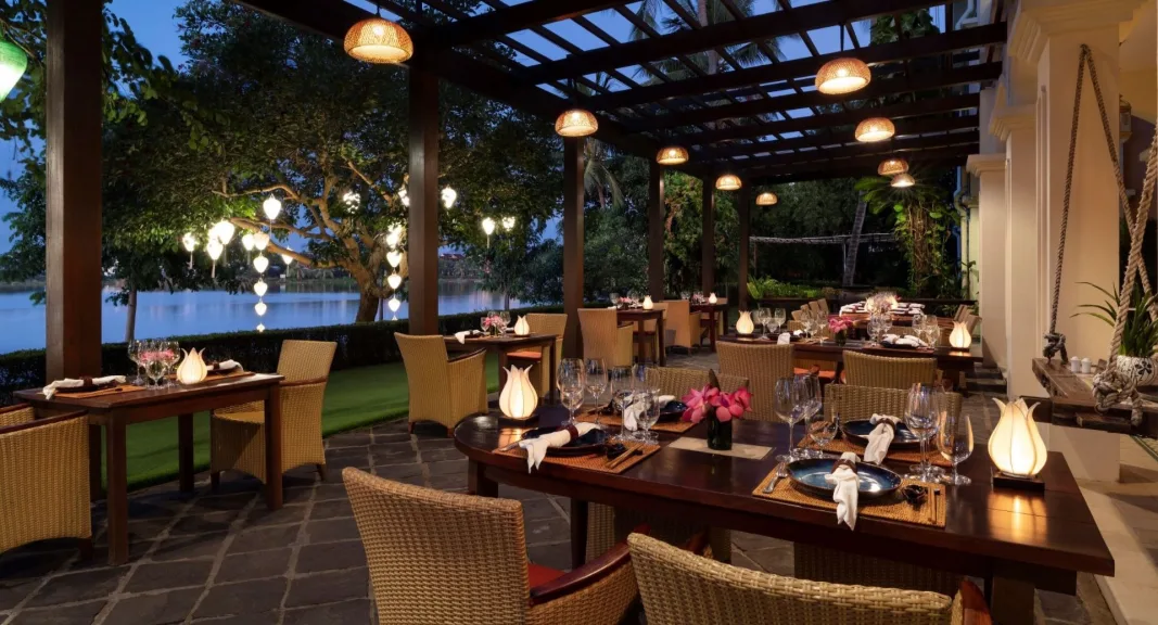 Lantern-lit riverside restaurant terrace overlooking Thu Bon River at Anantara Hoi An Resort during evening dining.