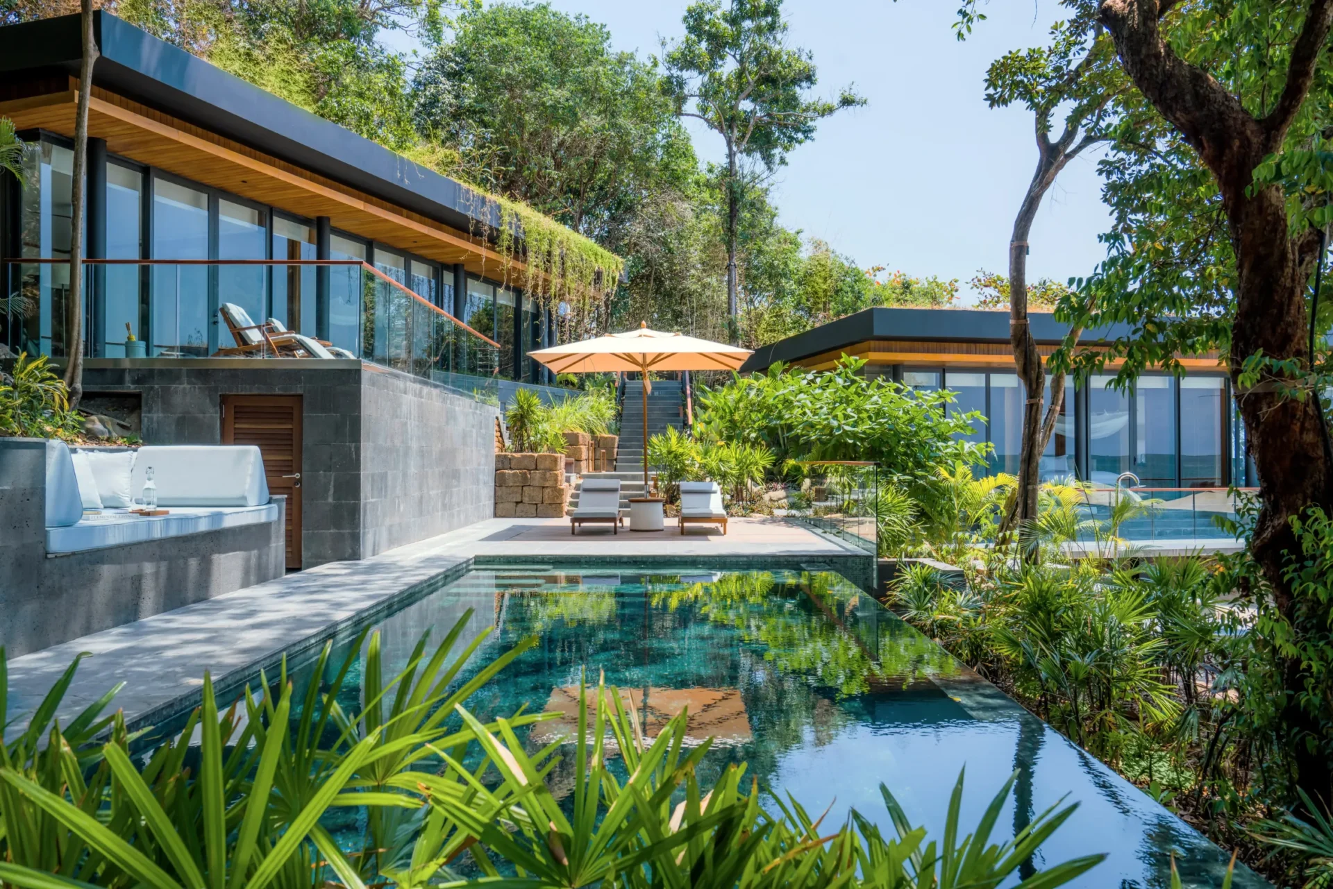A serene villa setting at Six Senses Krabey Island, featuring an open-air terrace embraced by tropical greenery and tranquil water elements.