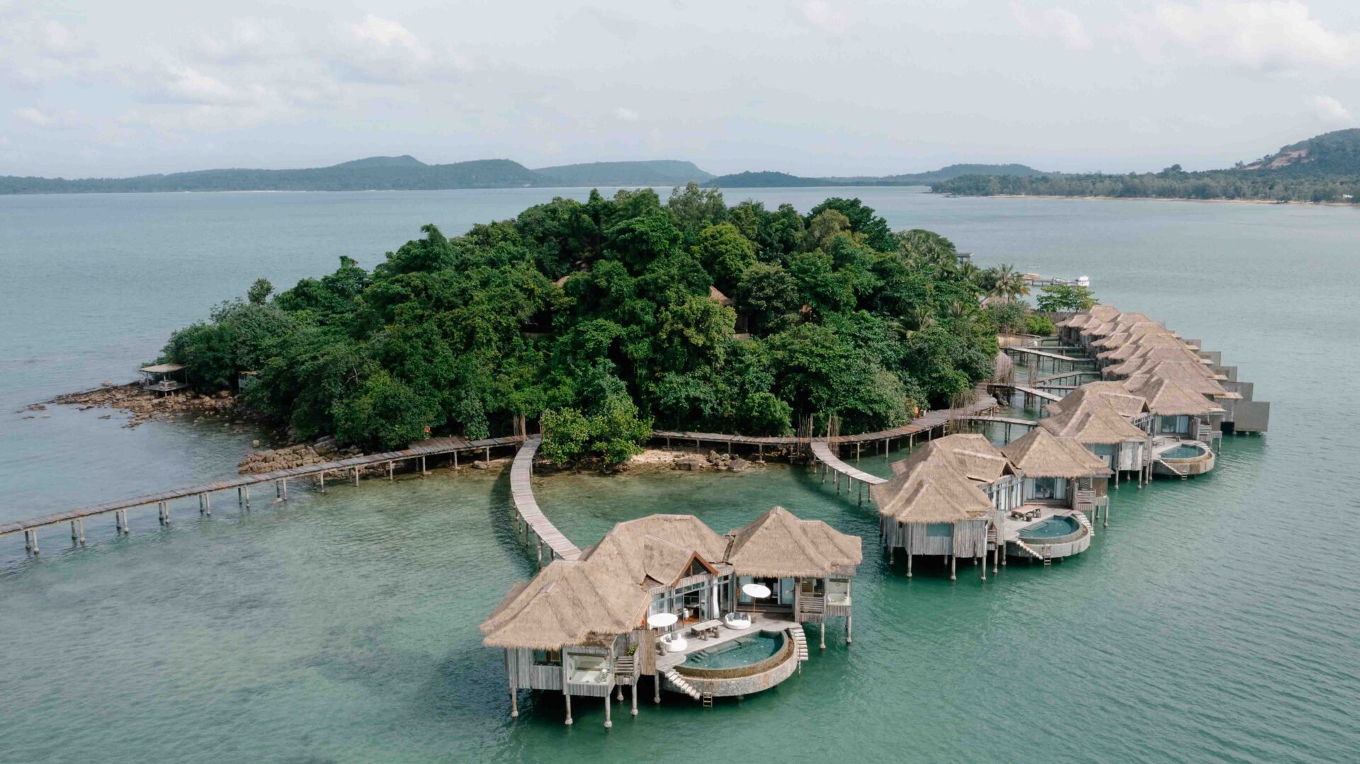Aerial view of Song Saa Private Island with overwater villas surrounded by turquoise sea and lush tropical forest in Cambodia