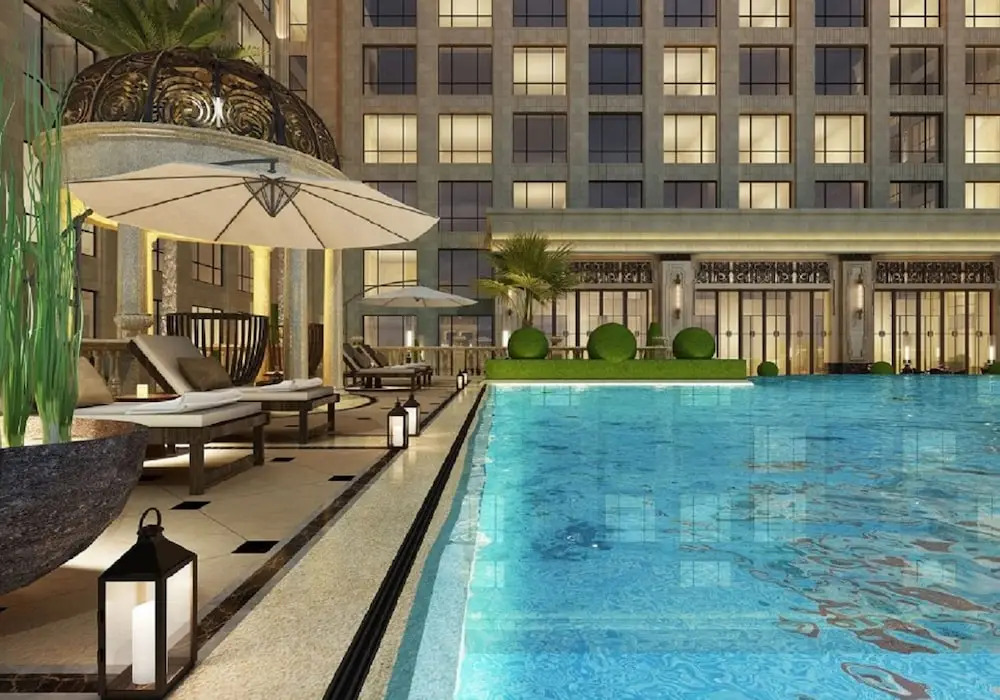 Outdoor swimming pool at Jin Bei Palace Hotel illuminated in the evening, creating a refined city hotel atmosphere