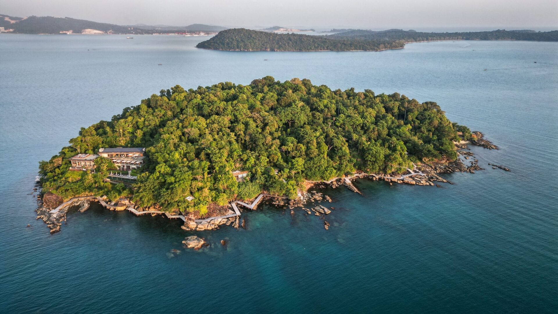 Aerial view of Six Senses Krabey Island, a luxury private island resort in Cambodia, surrounded by lush tropical forest and crystal-clear turquoise waters. 