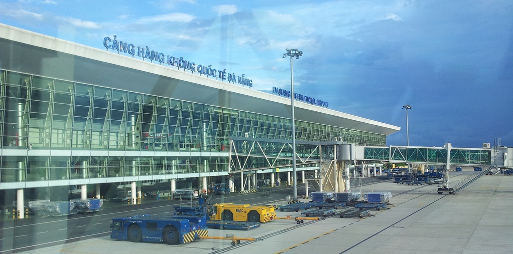 Da Nang International Airport Vietnam terminal with glass facade and aircraft ground service equipment on the runway