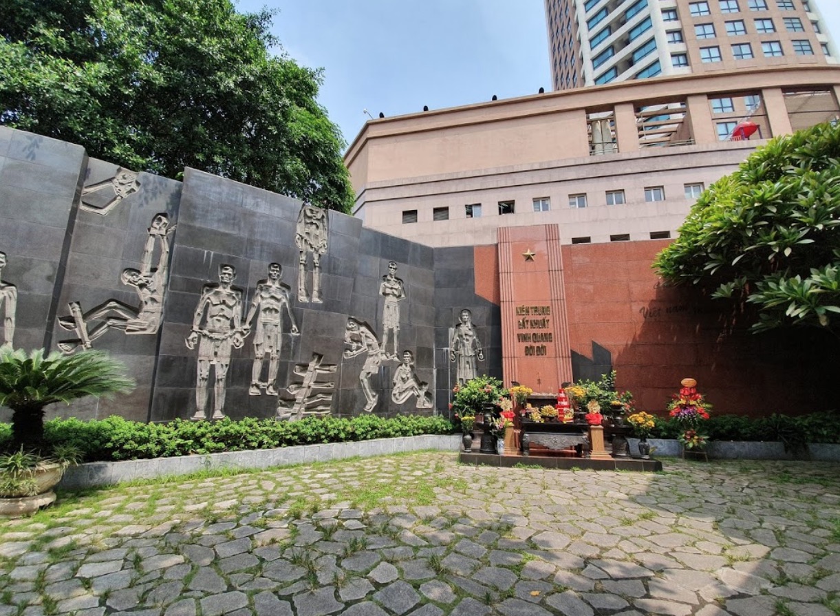 Memorial wall relief carving depicting Vietnamese soldiers and a commemorative monument inside the former Hoa Lo Prison compound