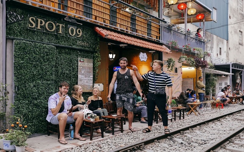 Tourists relaxing at cafés along Hanoi train street tracks