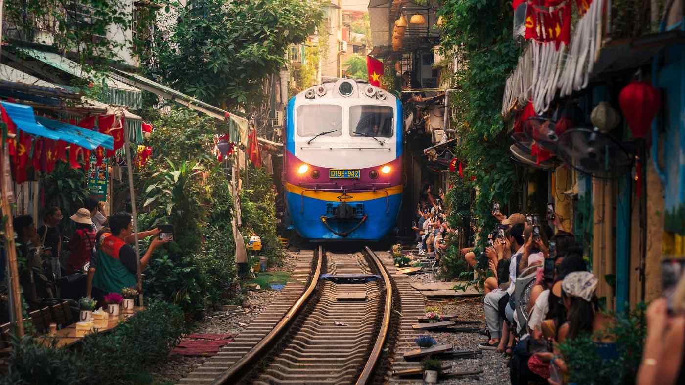Train passing through Hanoi train street crowded with visitors