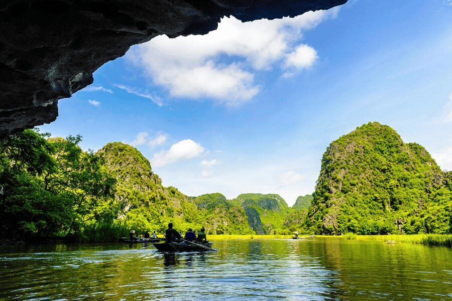 Tourists in small rowing boats exploring the Trang An Grottoes in Ninh Binh, a scenic landscape and one of the top nature-based things to do in Vietnam
