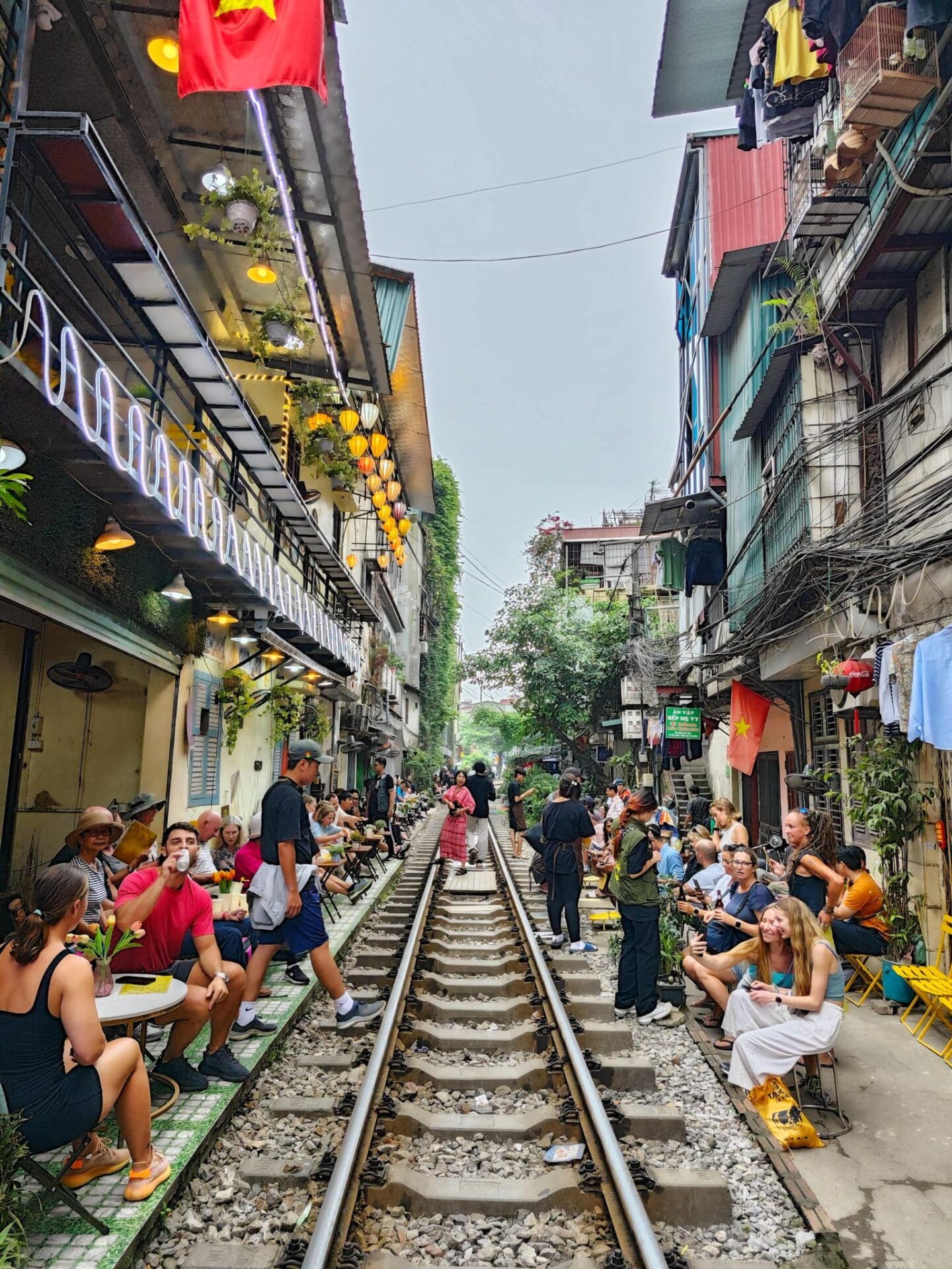 Visitors enjoying coffee along Hanoi train street railway