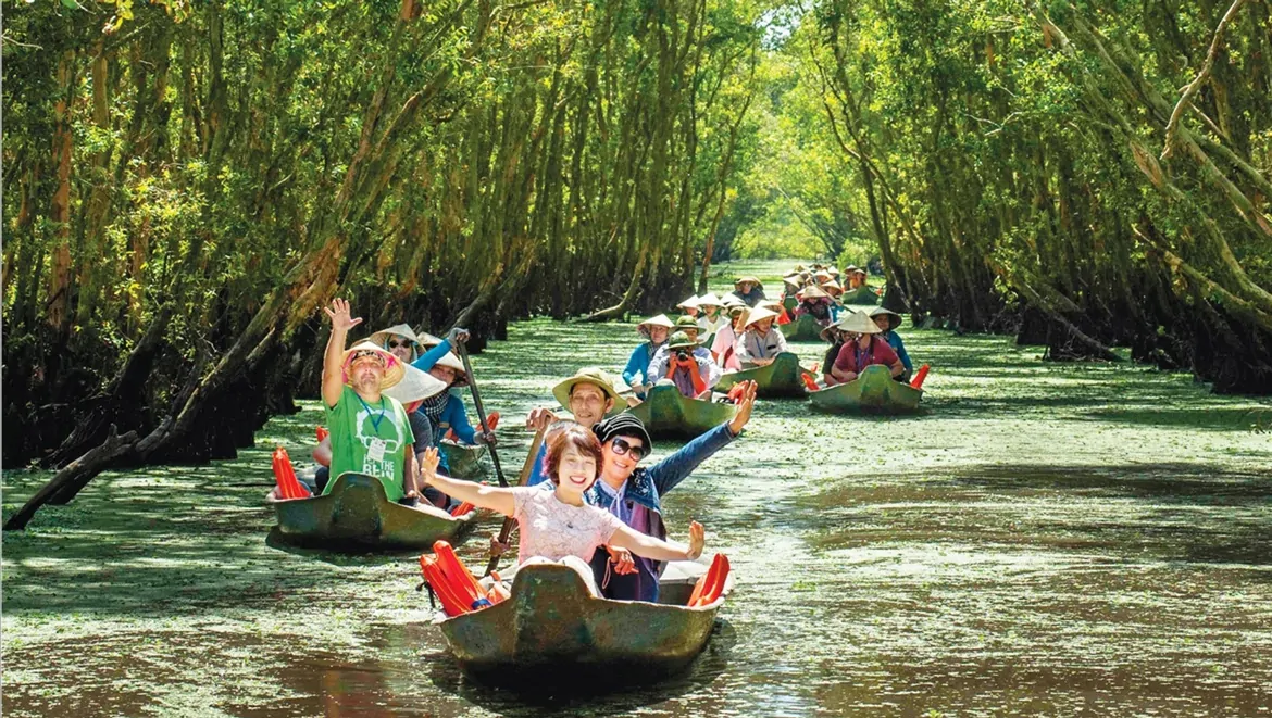 Scenic boat ride through a lush, green flooded forest in the Mekong Delta - A highlight in Vietnam Tours for Seniors​