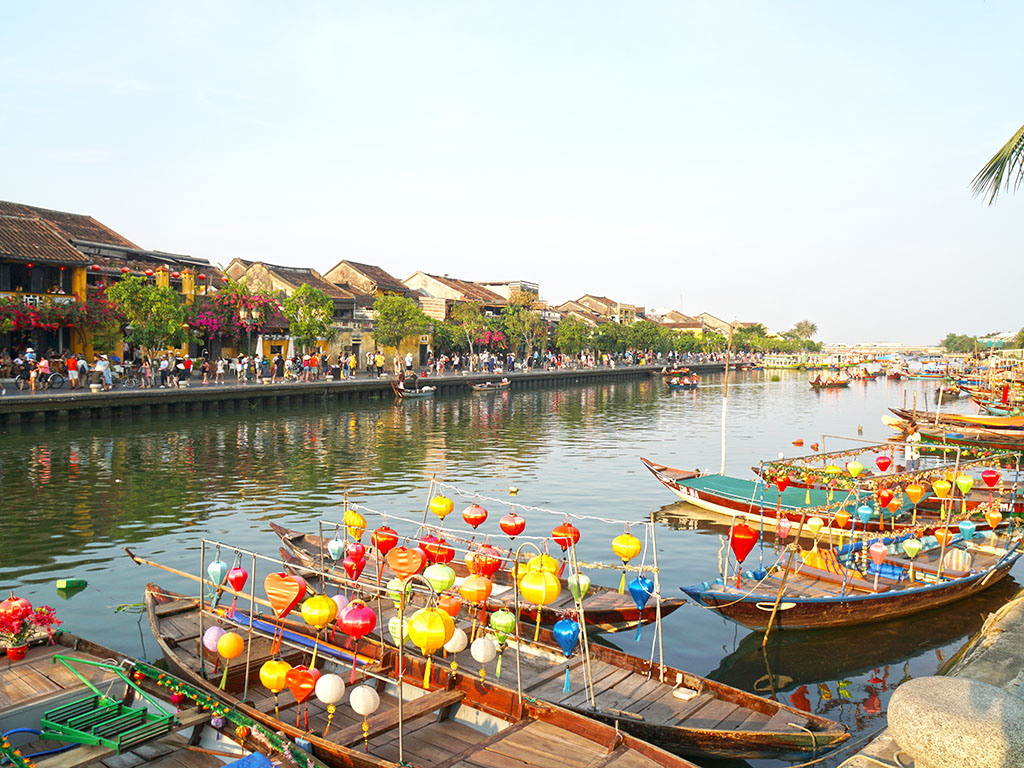 Colorful wooden boats decorated with lanterns docked along the river in Hoi An's Ancient Town, one of the most charming things to do in Vietnam